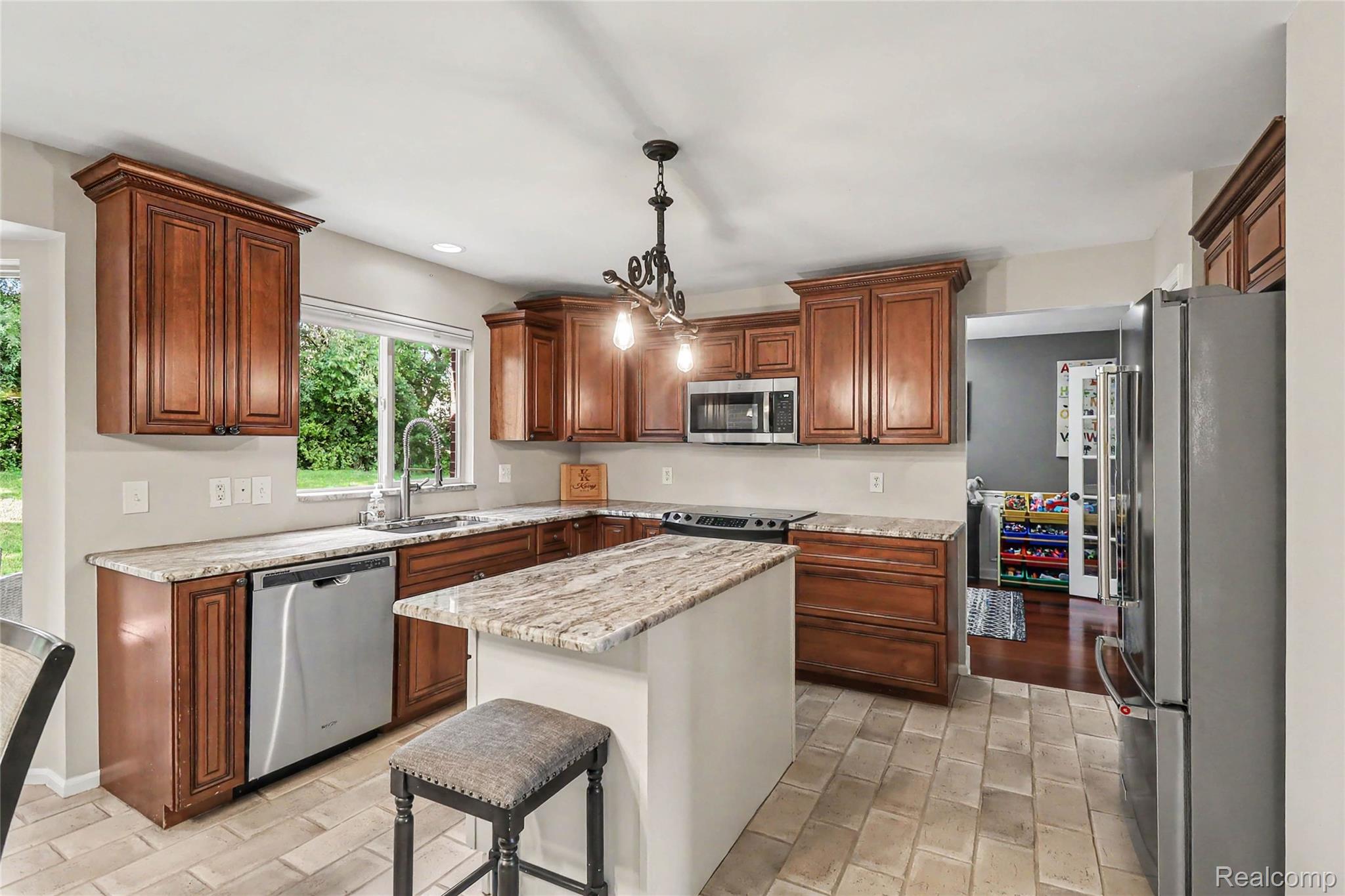 2548 Empire Court Rochester, MI 48309 - Photo 10 of 40 Kitchen featuring a central island with countertop seating, wood-finish cabinetry, stainless steel appliances, and light-toned tile flooring