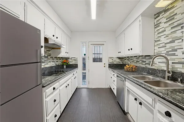 a kitchen with granite countertop a sink stove and cabinets