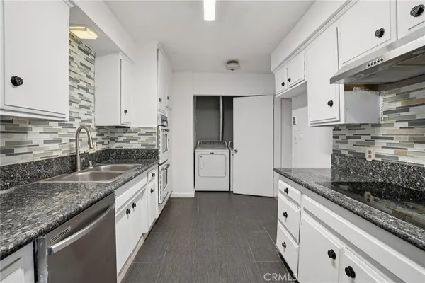a kitchen with granite countertop a sink stove and cabinets