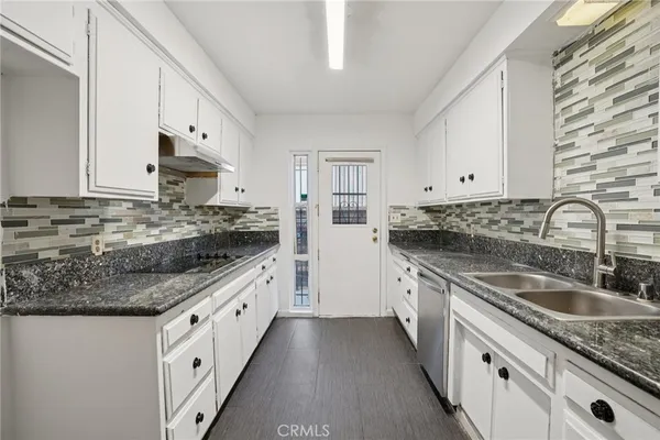 a kitchen with granite countertop a sink stove and cabinets