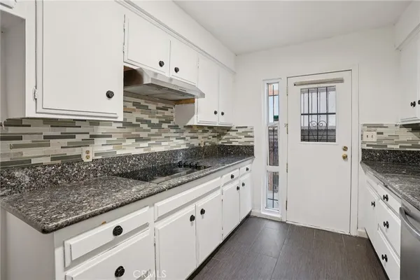 a kitchen with granite countertop a white cabinets and white appliances