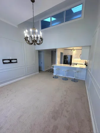 a view of a livingroom with a fireplace a kitchen sink and chandelier