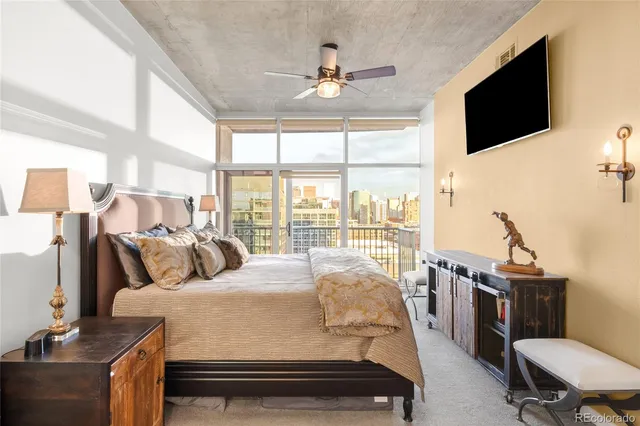 a bedroom with a bed a flat screen tv and a large window