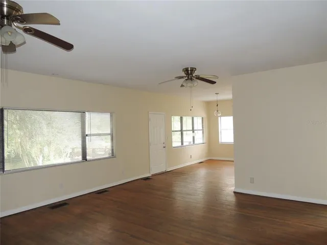 a view of an empty room with a window and wooden floor