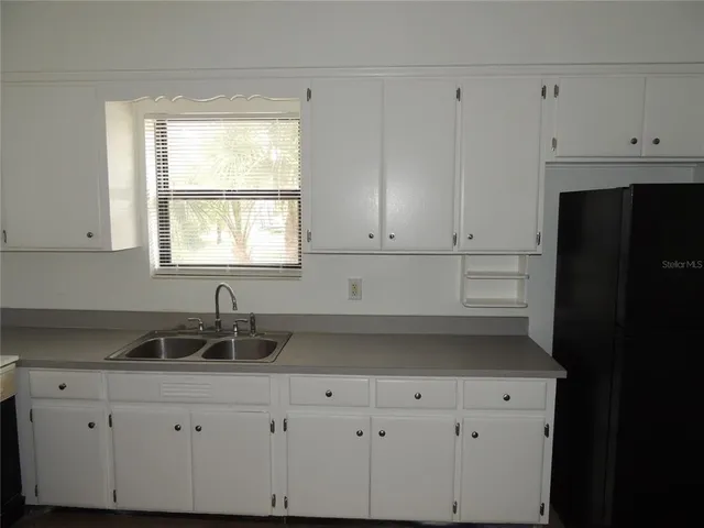 a kitchen with granite countertop white cabinets and sink