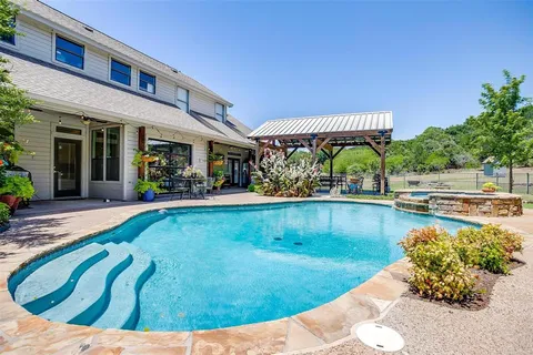 a view of a swimming pool with lawn chairs and plants