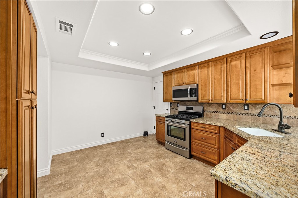9862 Solazzo Drive Rancho Cucamonga, CA 91730 - Photo 12 of 30 a kitchen with stainless steel appliances granite countertop a sink stove and refrigerator