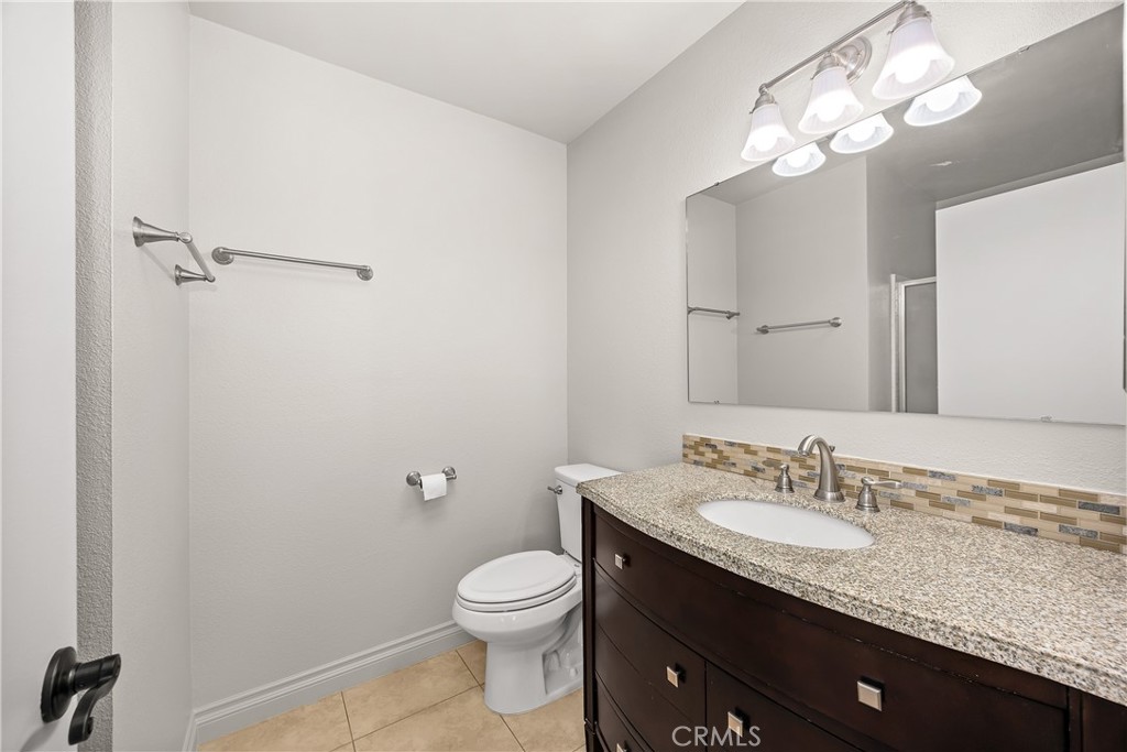 9862 Solazzo Drive Rancho Cucamonga, CA 91730 - Photo 26 of 30 a bathroom with a granite countertop sink a toilet and a mirror