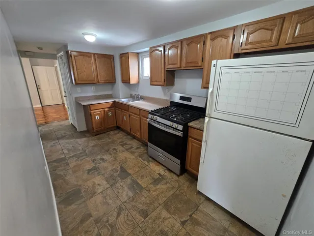 a kitchen with stainless steel appliances granite countertop a refrigerator stove a sink dishwasher and wooden cabinets