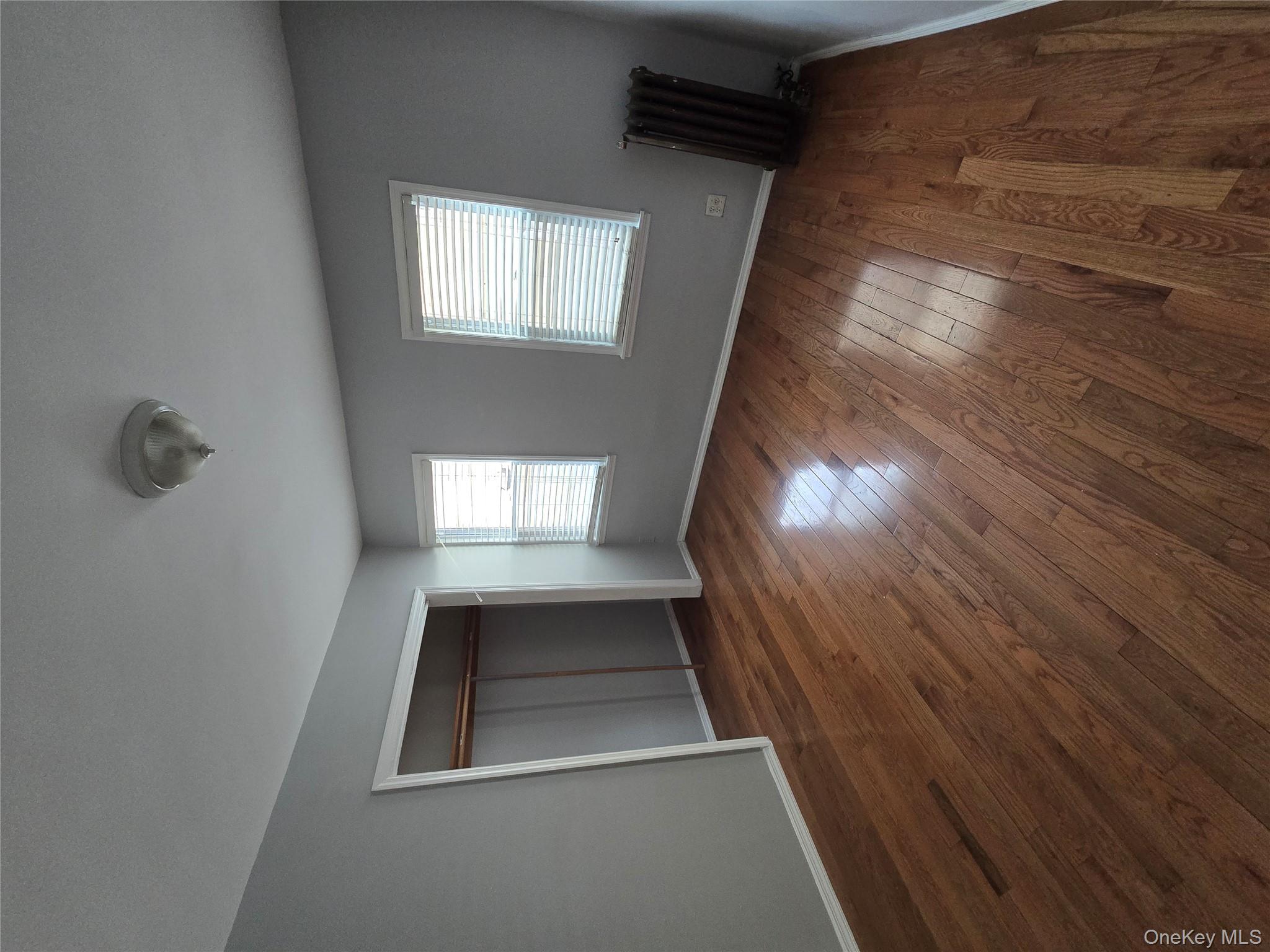 115-29 198th Street, Unit 1 Queens, NY 11412 - Photo 6 of 12 a view of an empty room with wooden floor and a window