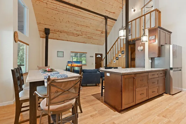 a dining hall with stainless steel appliances kitchen island granite countertop a dining table and chairs