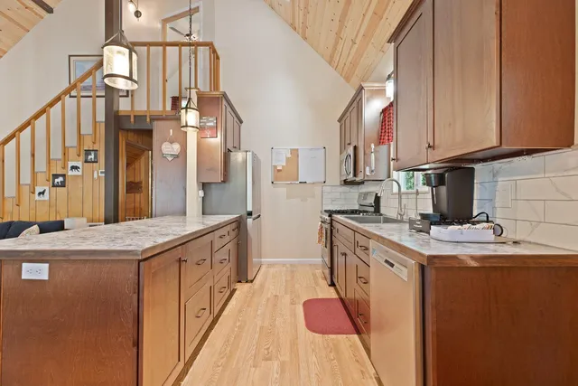 a kitchen with stainless steel appliances granite countertop a sink a stove and a wooden floors