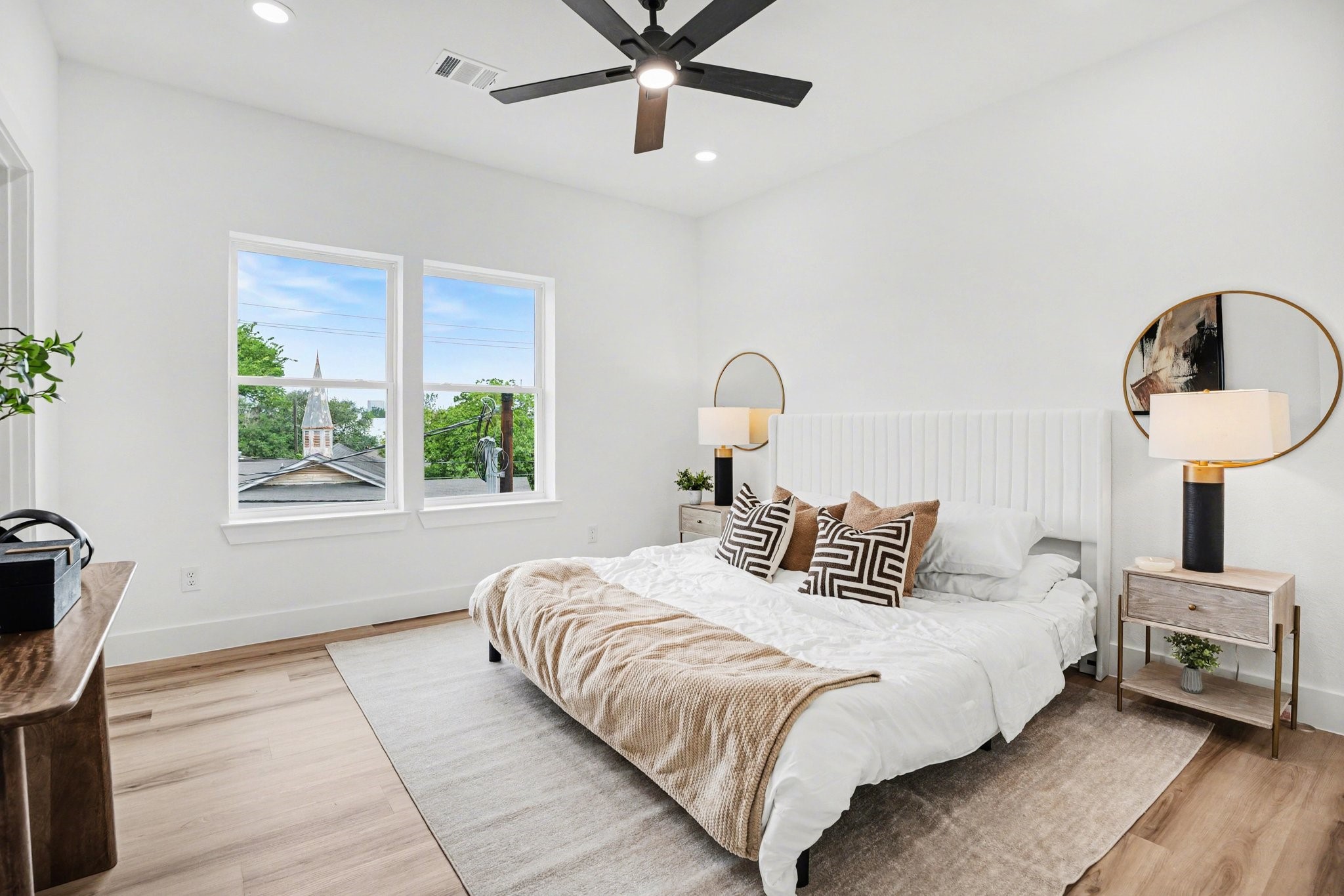 115 Milby Street Houston, TX 77003 - Photo 13 of 28 Bright and modern primary bedroom with large windows, wood flooring, and a ceiling fan, creating an inviting atmosphere.