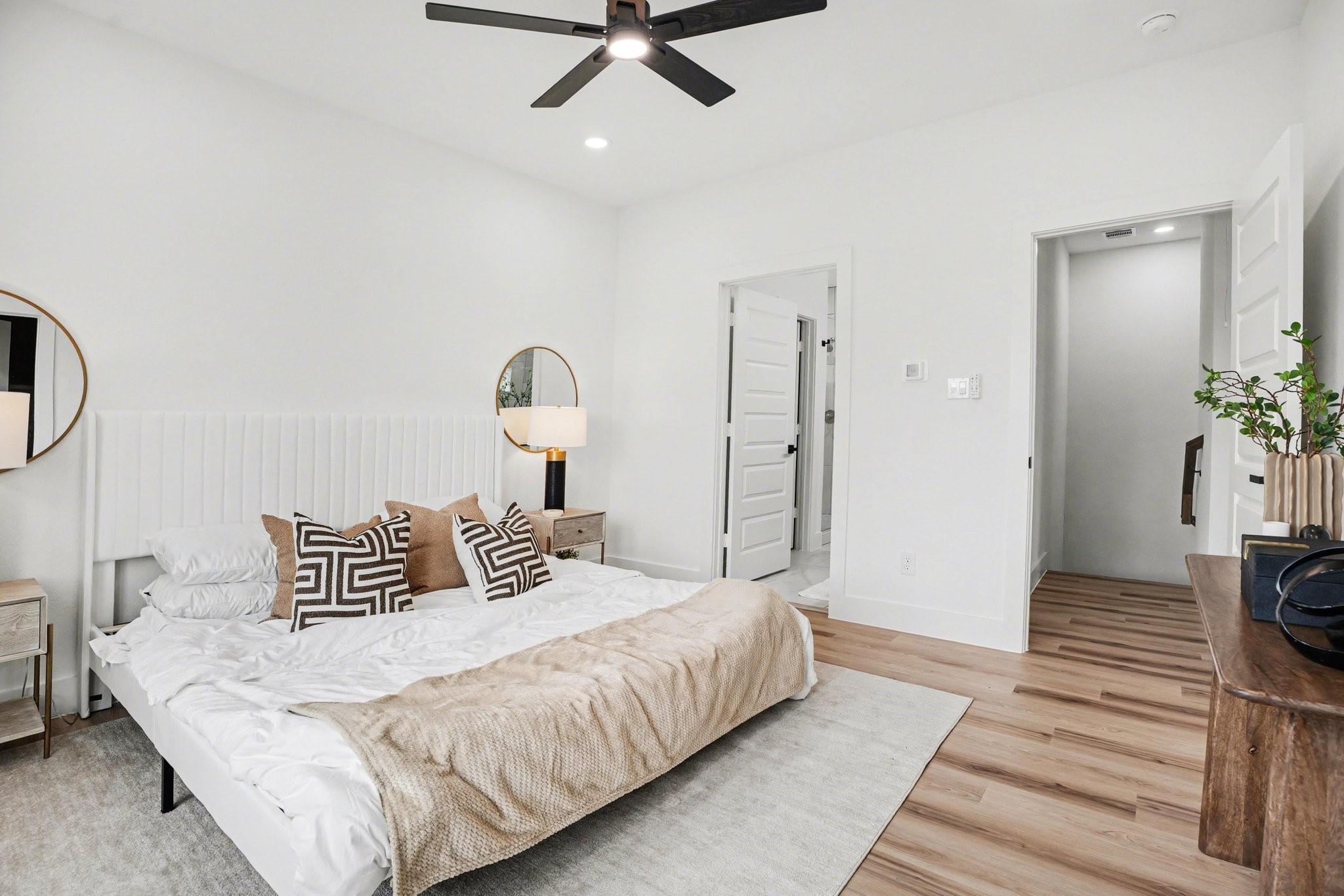 115 Milby Street Houston, TX 77003 - Photo 14 of 28 Bright and modern primary bedroom with large windows, wood flooring, and a ceiling fan, creating an inviting atmosphere.
