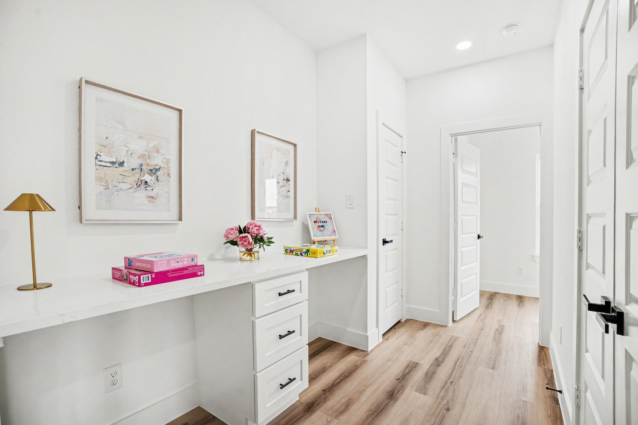 115 Milby Street Houston, TX 77003 - Photo 25 of 28 This photo showcases a bright hallway with white walls and wooden flooring. It features a built-in desk with drawers. The area is well-lit with recessed lighting.