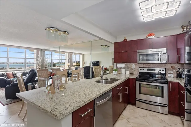 a kitchen with stainless steel appliances granite countertop a kitchen island a stove a sink a dining table and chairs