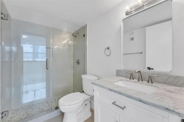 a bathroom with a granite countertop toilet a sink and a mirror