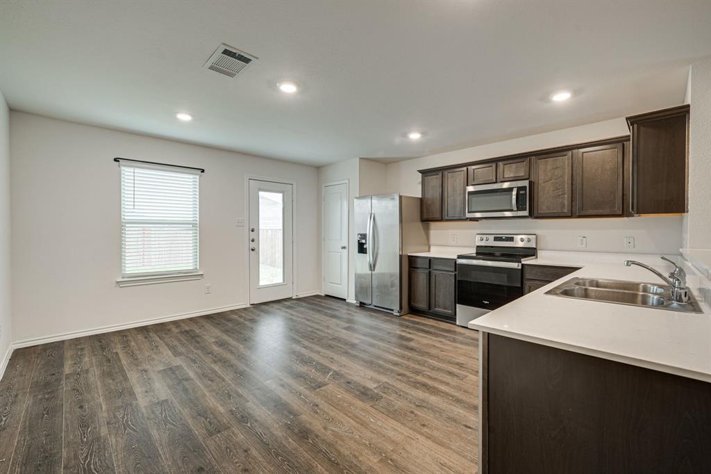 317 Sage Street Anna, TX 75409 - Photo 12 of 33 a kitchen with a sink a microwave a stove and refrigerator
