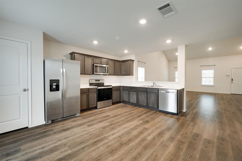 317 Sage Street Anna, TX 75409 - Photo 9 of 33 a large kitchen with stainless steel appliances granite countertop a large counter top and a stove