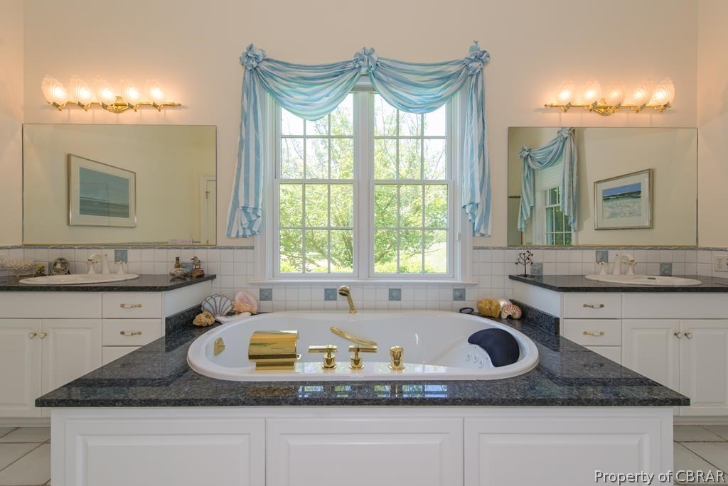 1193 West Point Road Lancaster, VA 22503 - Photo 35 of 50 a bathroom with a granite countertop sink a mirror and a bathtub with shower