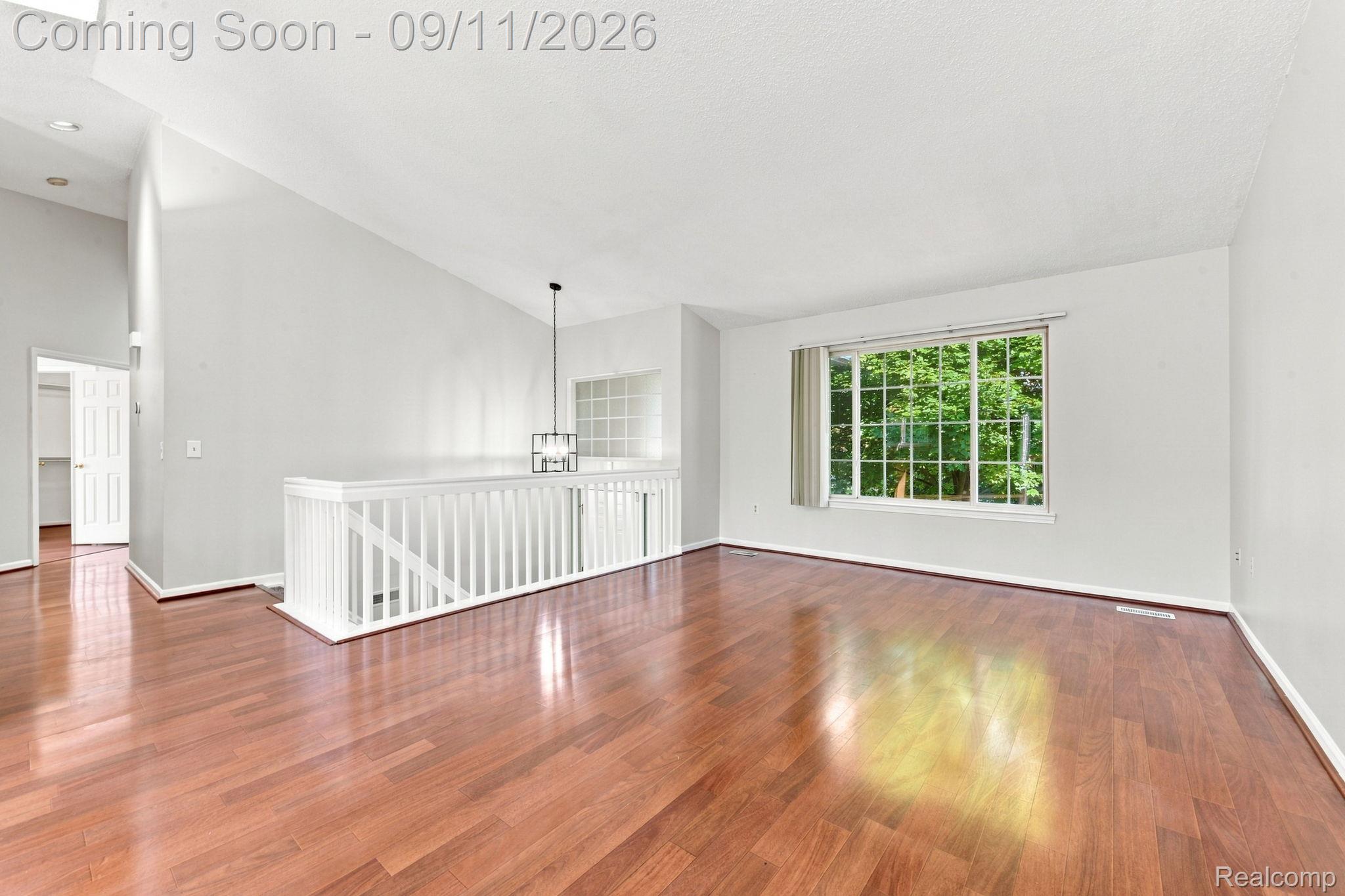 3201 Lynhurst Court Rochester, MI 48306 - Photo 9 of 43 Hardwood-finish flooring, white painted walls, vaulted ceiling with skylight, white baluster railing, and a multi-pane window