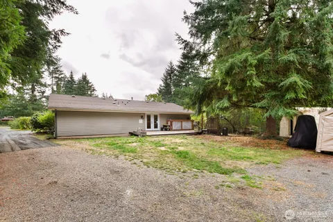 a view of a house with a yard and large tree