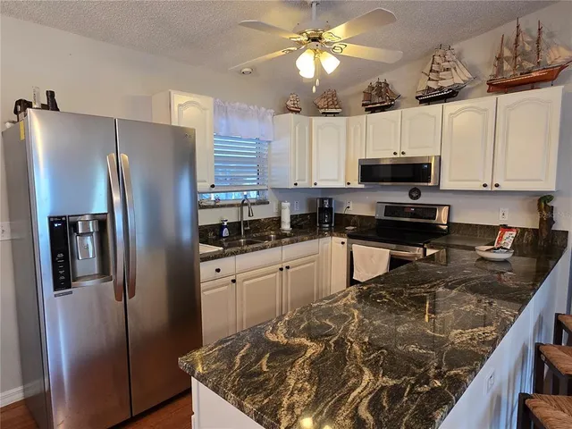 a kitchen with stainless steel appliances granite countertop a refrigerator a stove top oven a sink and dishwasher