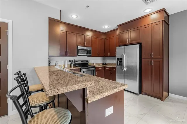 a kitchen with stainless steel appliances kitchen island granite countertop a sink refrigerator and cabinets