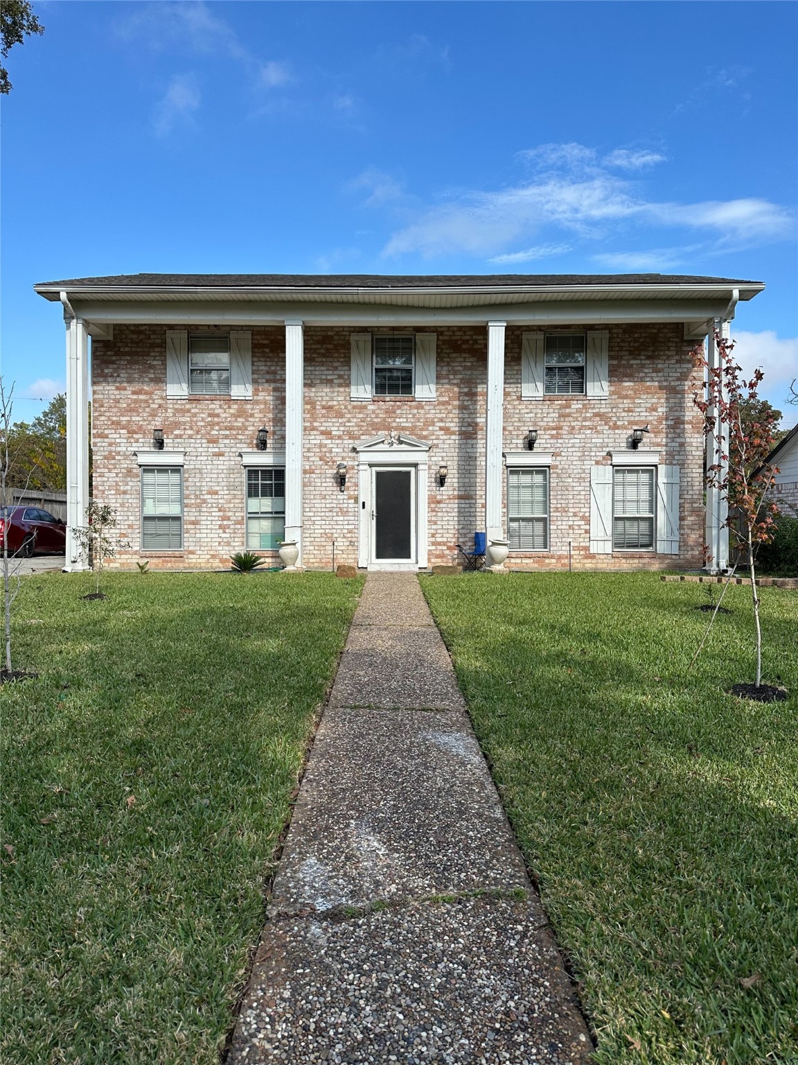 a view of a house with brick walls and a yard with a large tree