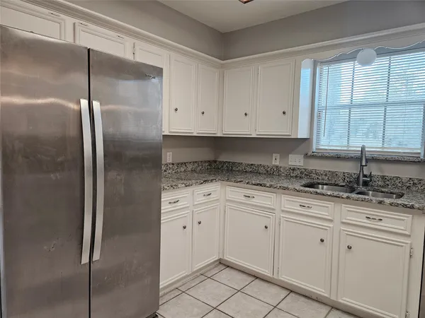 a kitchen with granite countertop a refrigerator sink and cabinets