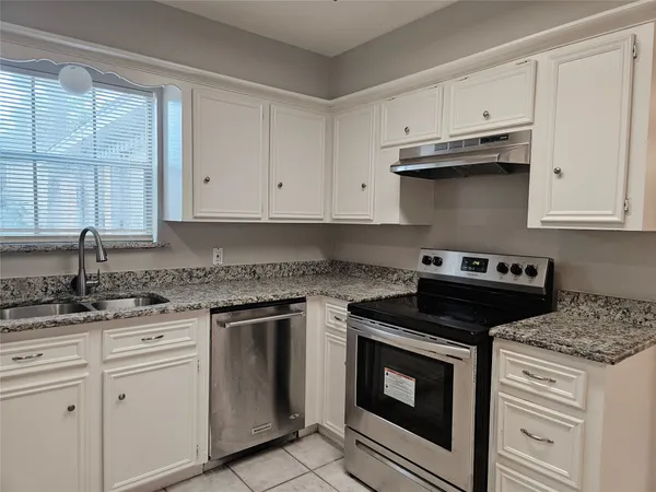 a kitchen with granite countertop white cabinets and stainless steel appliances