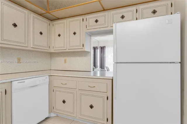 a kitchen with white cabinets and refrigerator