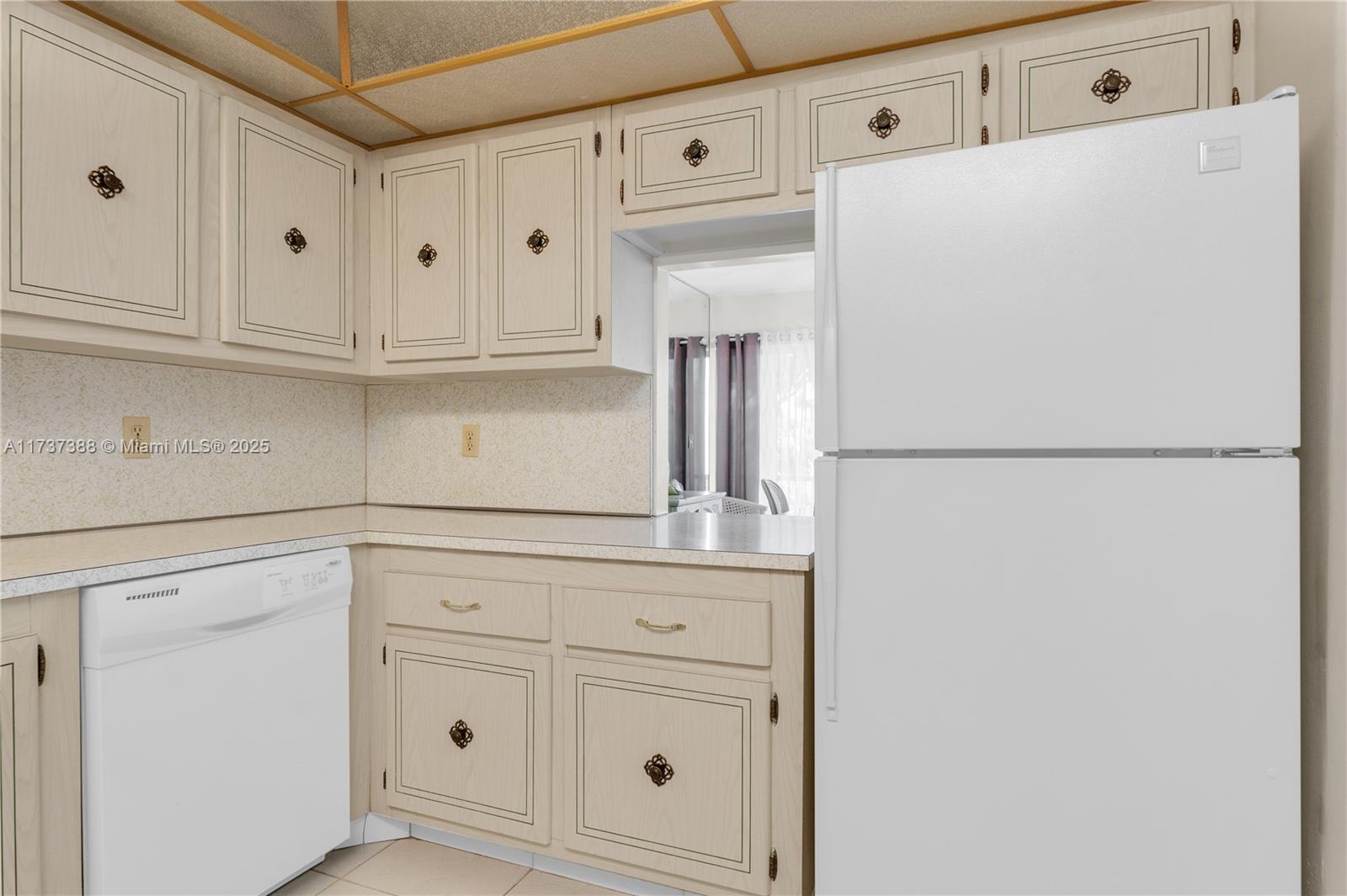 200 Diplomat Parkway, Unit 229 Hallandale Beach, FL 33009 - Photo 7 of 30 a kitchen with white cabinets and refrigerator