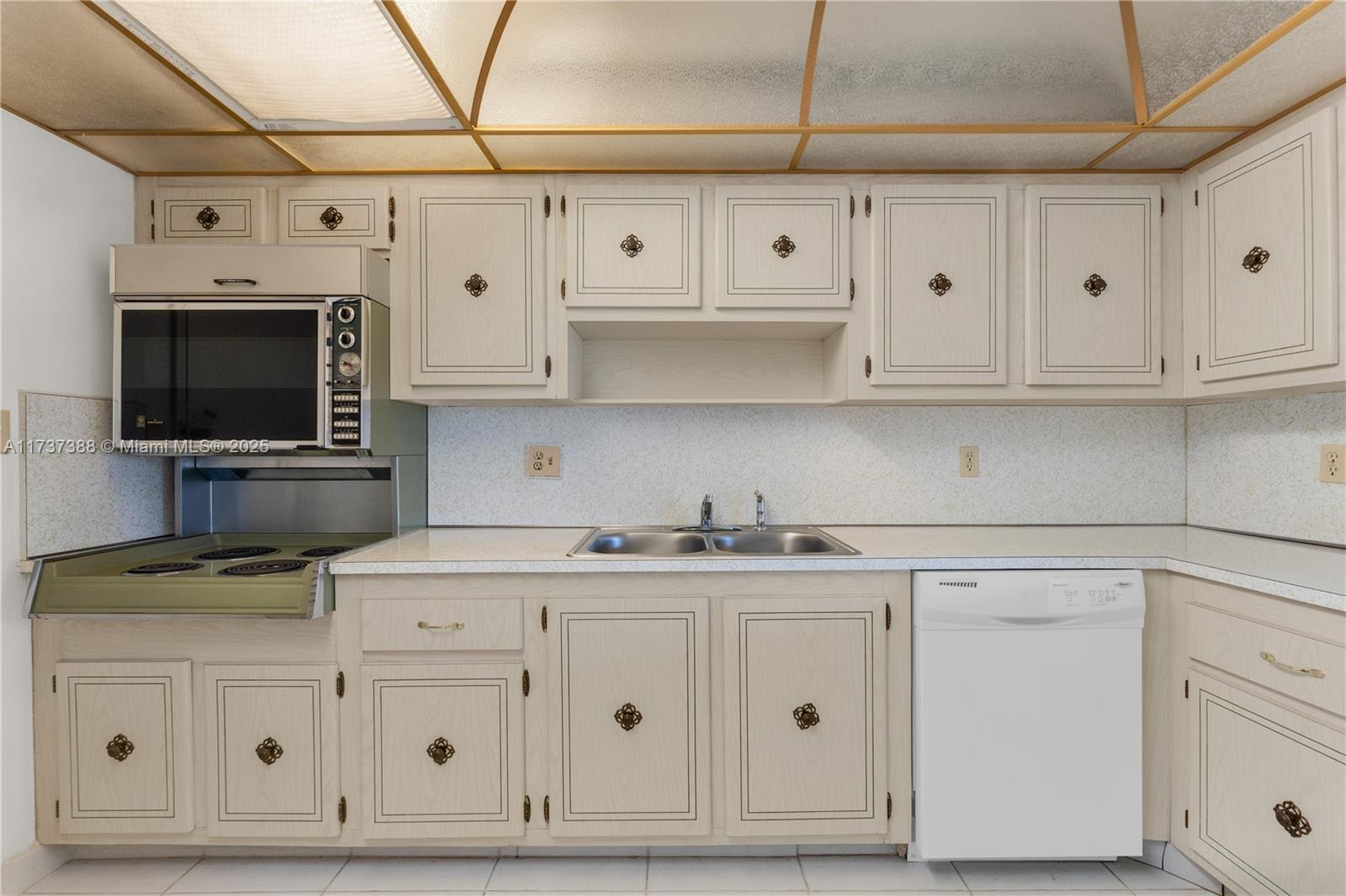 200 Diplomat Parkway, Unit 229 Hallandale Beach, FL 33009 - Photo 9 of 30 a kitchen with white cabinets and appliances