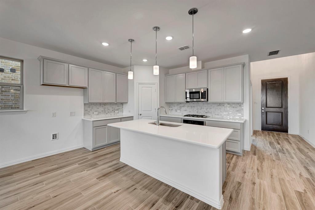 3704 Water Lily Way Prosper, TX 75078 - Photo 12 of 40 a kitchen with kitchen island a sink stainless steel appliances and cabinets