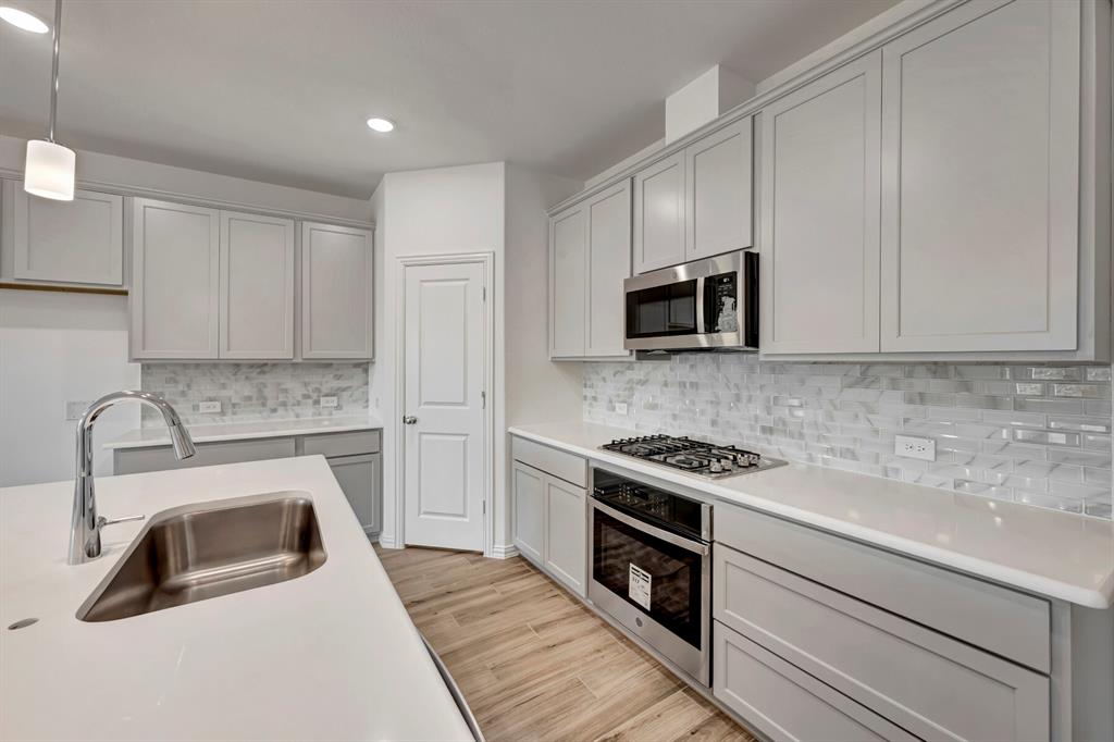 3704 Water Lily Way Prosper, TX 75078 - Photo 3 of 40 a kitchen with granite countertop white cabinets and stainless steel appliances