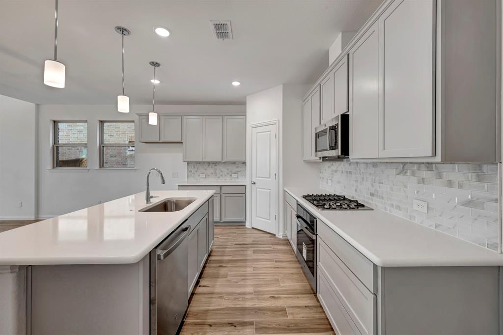 3704 Water Lily Way Prosper, TX 75078 - Photo 8 of 40 a kitchen with stainless steel appliances granite countertop a sink a stove and a refrigerator