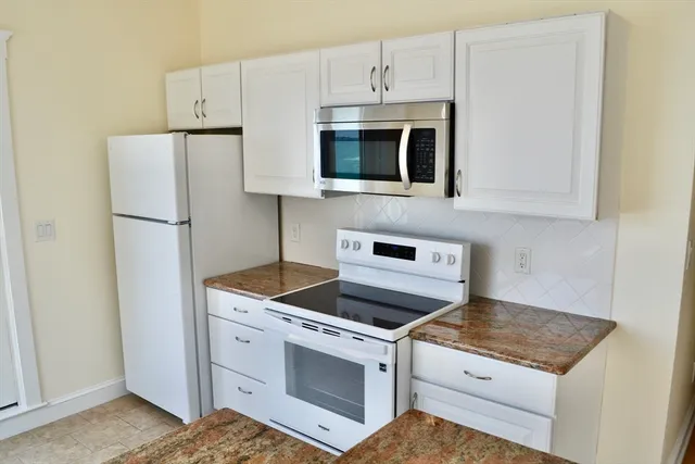 a kitchen with white cabinets and white appliances