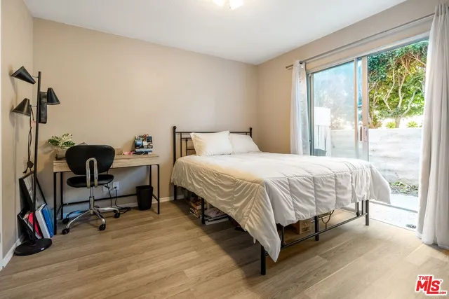 a bedroom with a bed a flat screen tv and a large window