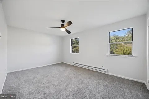 an empty room with windows and fan