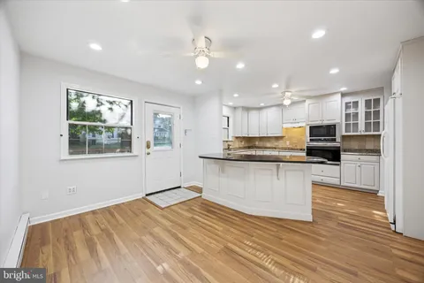 a open kitchen with kitchen island a sink dishwasher stove and refrigerator with wooden floor