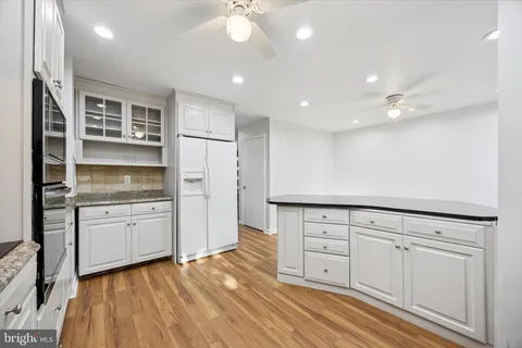 a open kitchen with granite countertop white cabinets and white appliances