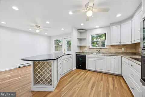a kitchen with granite countertop a sink cabinets stainless steel appliances and a window