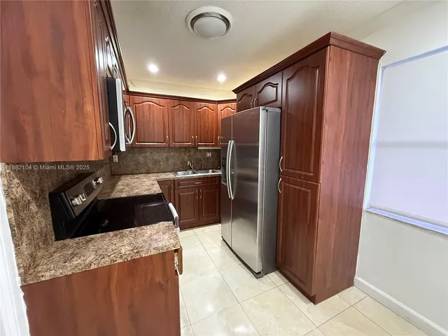 a kitchen with stainless steel appliances granite countertop a refrigerator and a sink