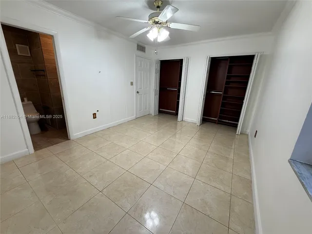 a view of an empty room with closet and a ceiling fan