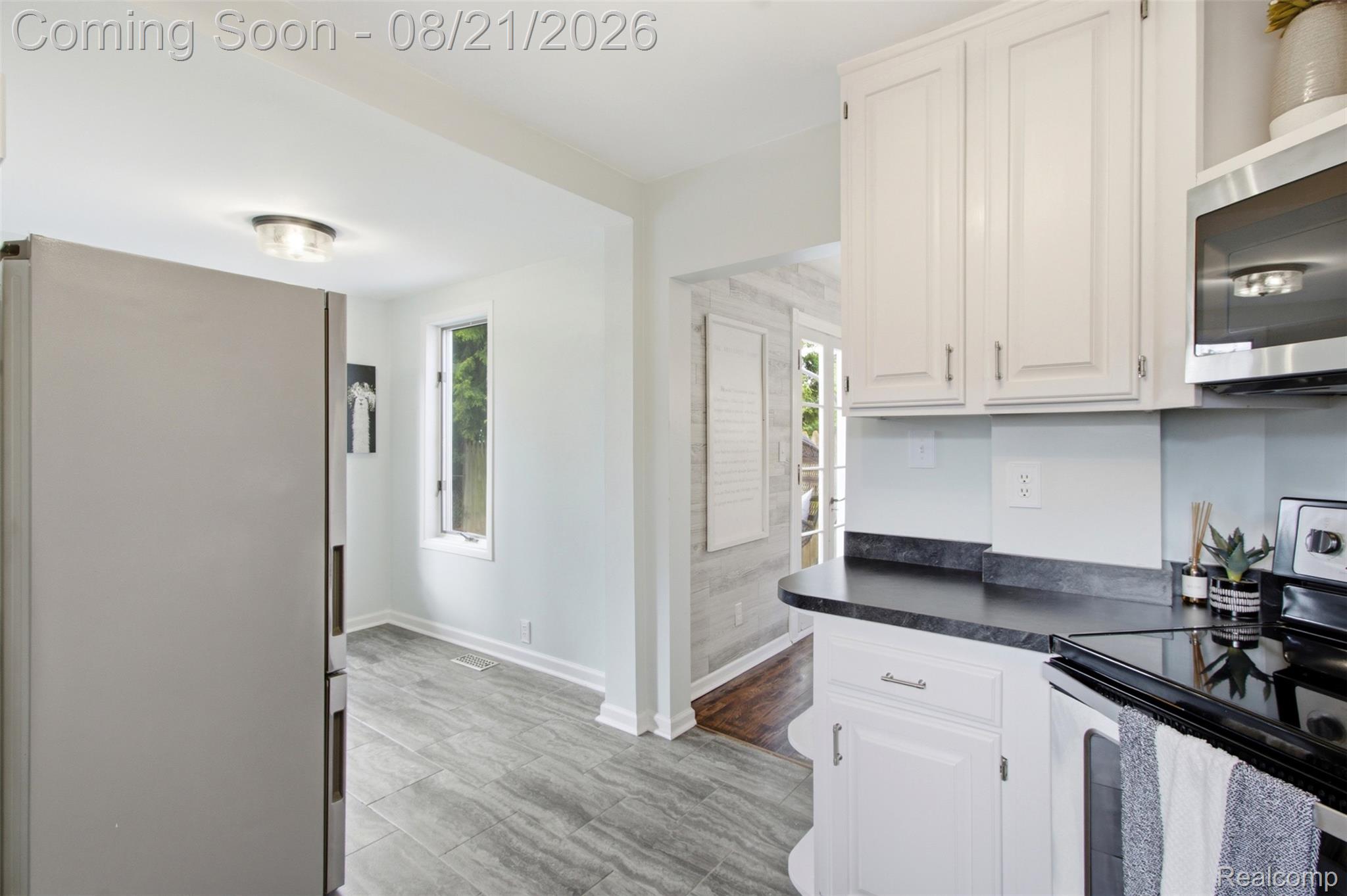 1383 Princeton Road Berkley, MI 48072 - Photo 10 of 28 White cabinetry with brushed nickel hardware, dark countertops, wood-finish flooring, and a stainless steel refrigerator