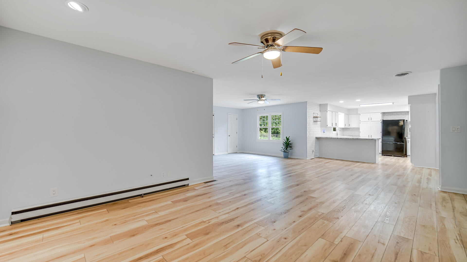 6717 State Rte 49 Rensselaer, IN 47978 - Photo 17 of 31 an empty room with wooden floor chandelier fan and windows