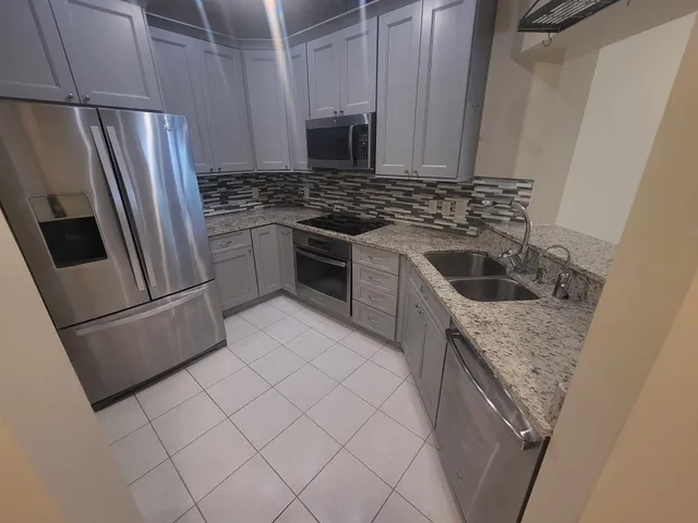 a kitchen with granite countertop a refrigerator sink and stove