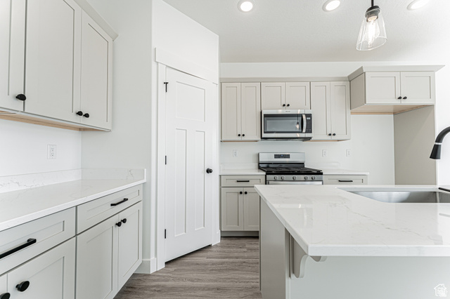 4774 Alder Drive Mapleton, UT 84664 - Photo 5 of 27 Kitchen featuring light stone countertops, stainless steel appliances, light wood finished floors, and hanging light fixtures