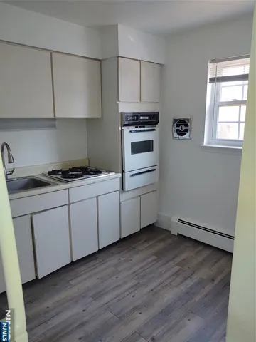a kitchen with white cabinets stove and sink